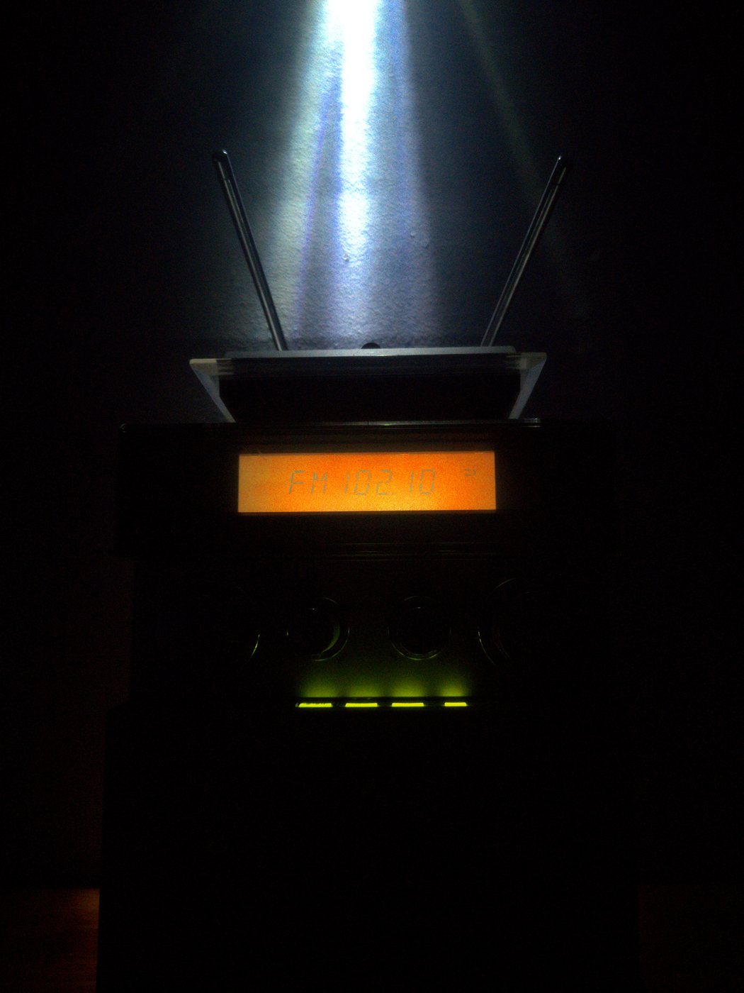 A home stereo tuned to FM 102.1 in the dark, antennas up