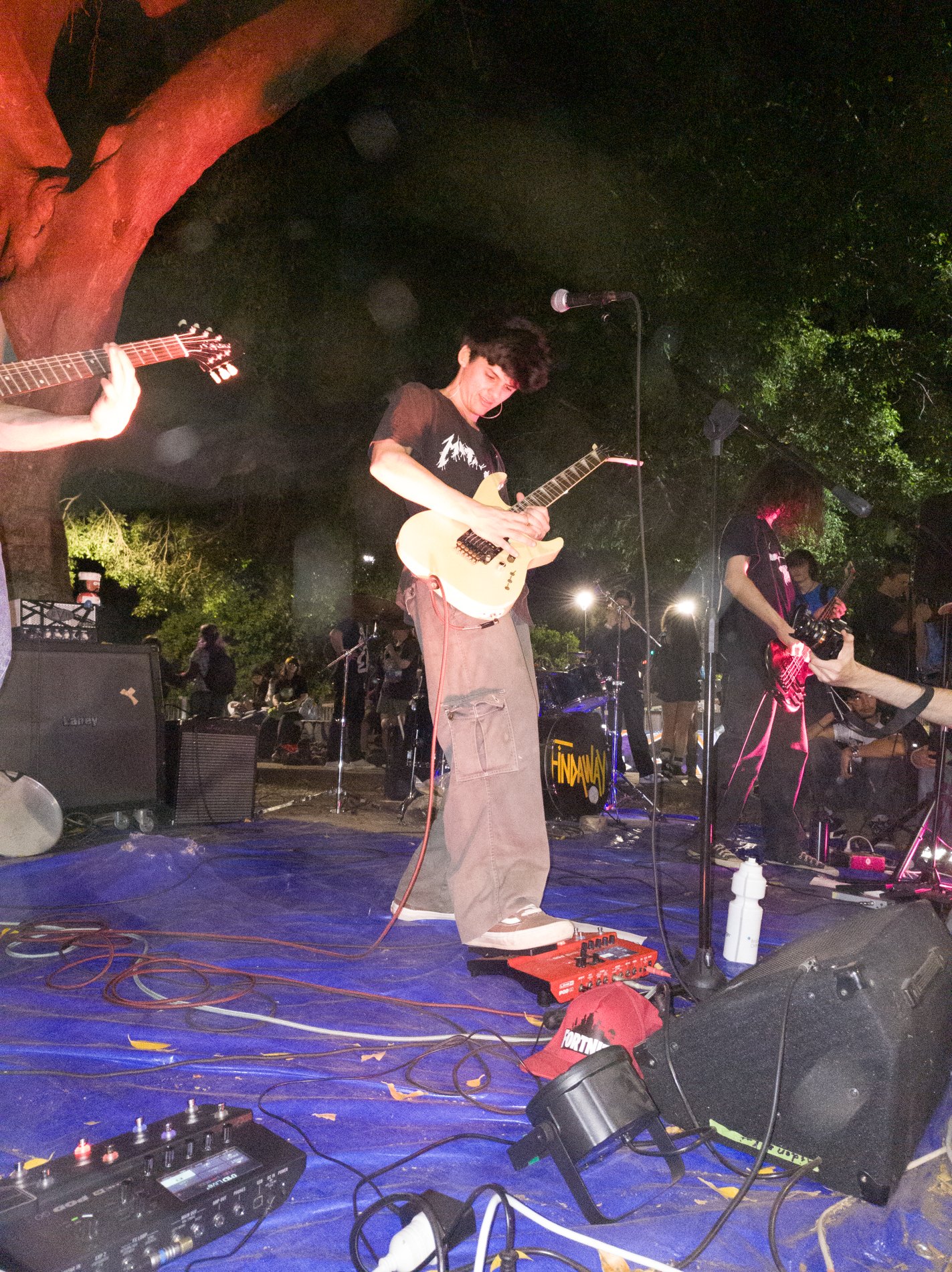A guitarist mid-set on a tarp-covered stage at Punk in the Park